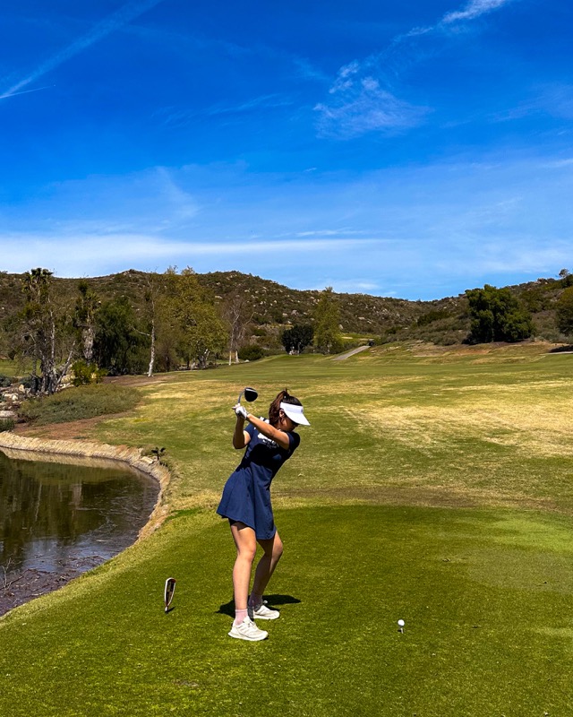 Stella mid-swing on a golf course
