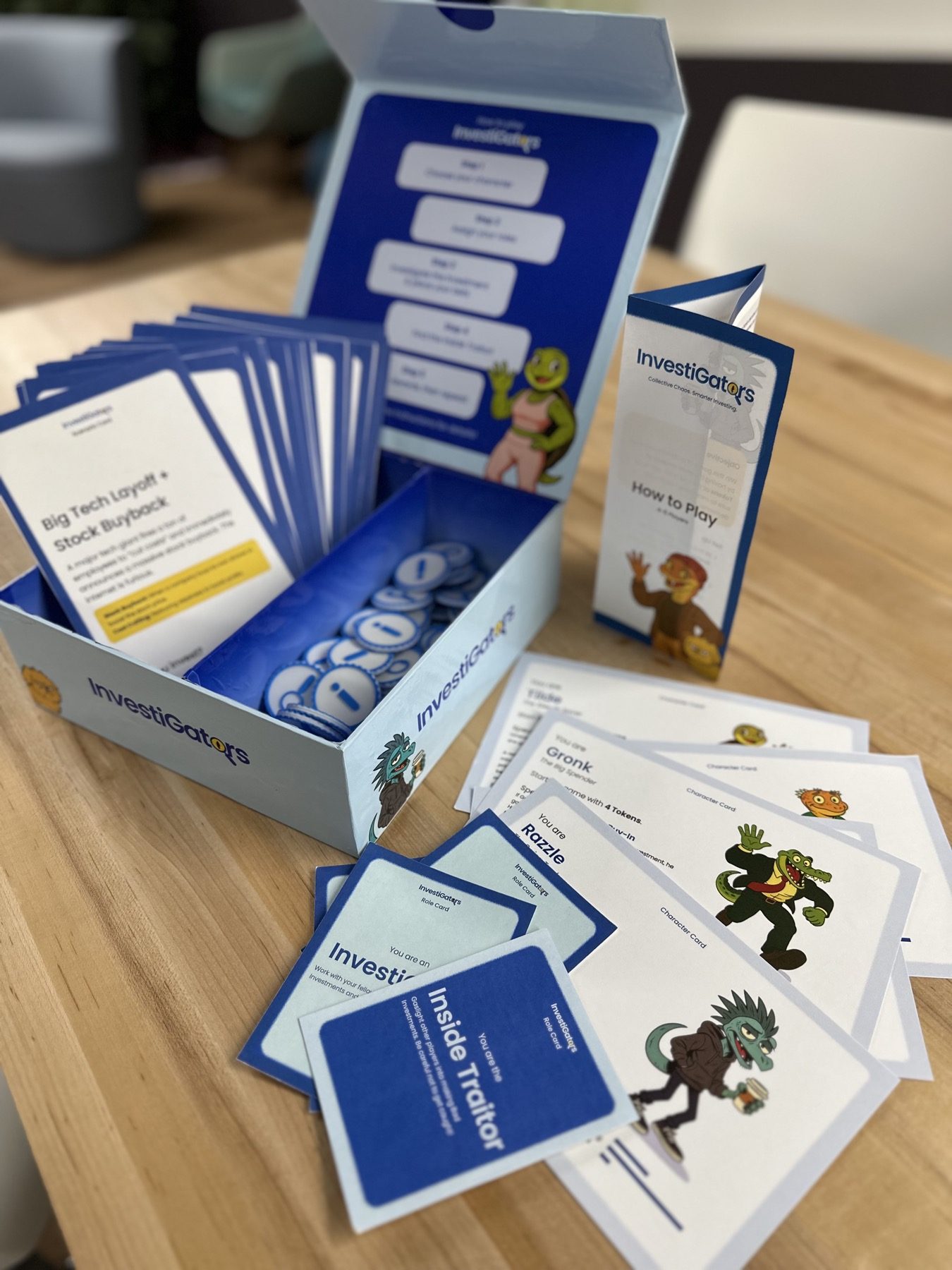 The box open on a wooden table: scenario deck, a pile of tokens, the how-to-play leaflet, and character cards fanned out