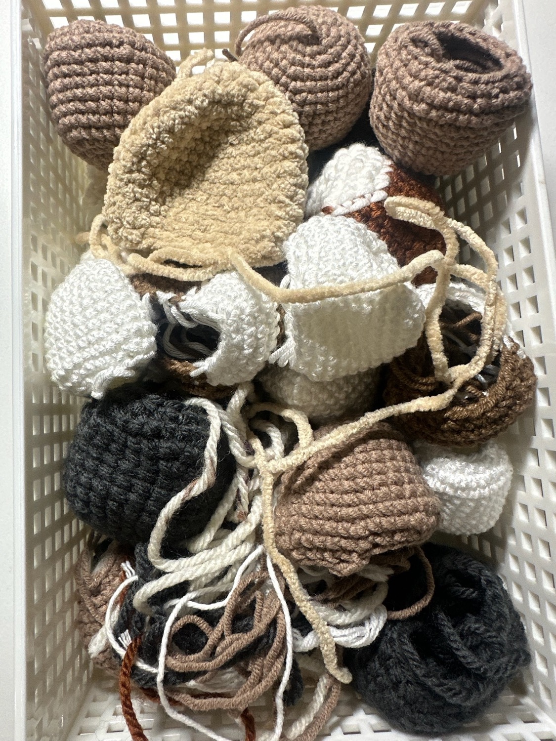 A basket of crocheted prototype heads and parts in different yarns